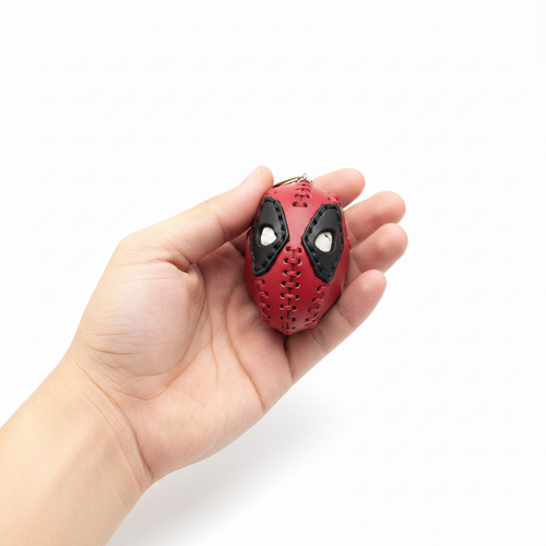 Handcrafted leather Deadpool head keyring held in hand to show scale on white background