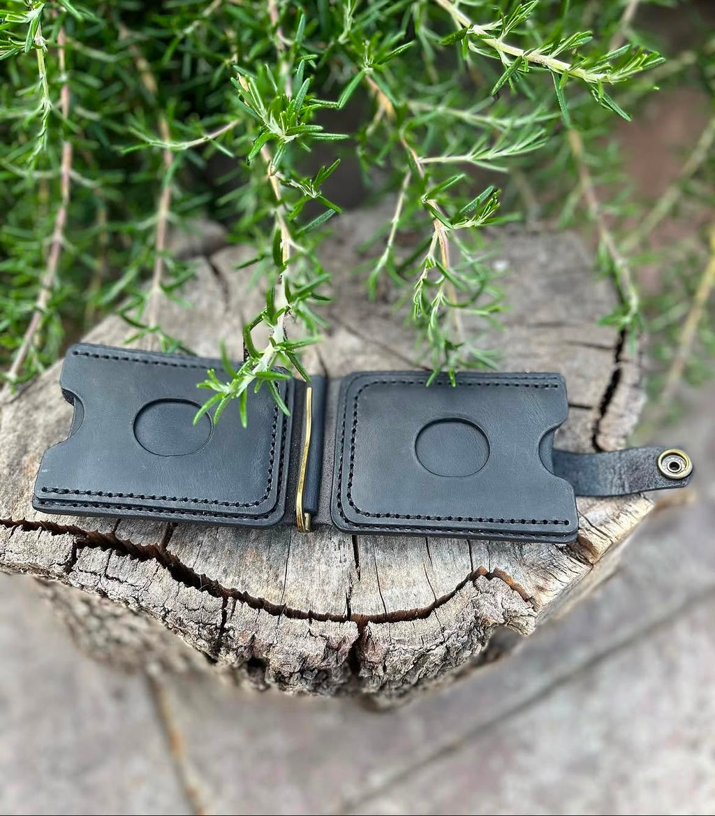 Black leather wallet open showing card slots, money clip and snap closure - lifestyle shot on wood stump